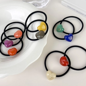 Detail view of colorful acrylic heart charms with gold text on high-elasticity hair ties