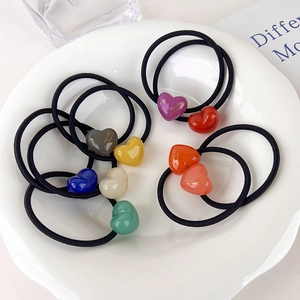 Close-up of colorful heart-shaped acrylic hair ties displayed in a white decorative tray