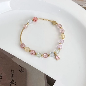 Detail of beaded bracelet featuring pastel strawberry crystals and star charm pendants