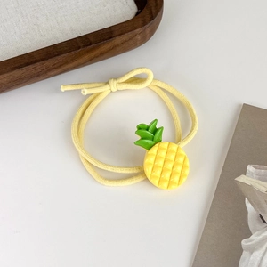 Détail d'un ornement en résine d'ananas jaune sur un élastique à cheveux double brin