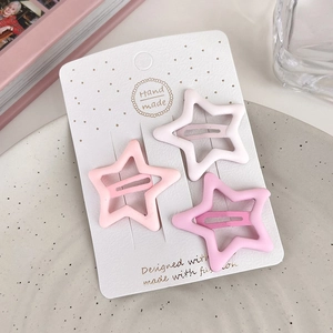 Detailed view of three matte star-shaped hair clips in pink and white on a display card