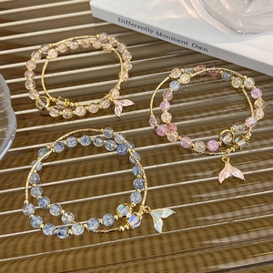 Detailed macro view of beaded bracelets with gradient mermaid tail charms on glass