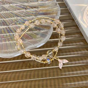 Detail of beaded bracelet with pink enamel mermaid tail pendant and peach crystals