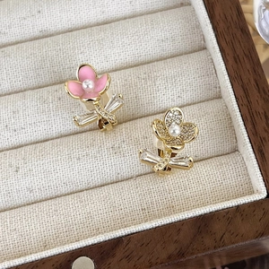 Close-up of asymmetrical flower earrings with pink enamel, zircons and white pearls