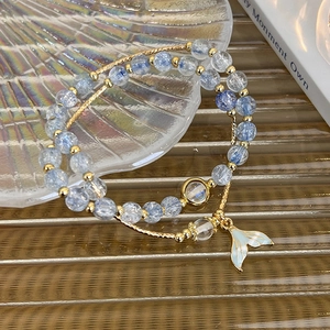 Detailed shot of double-layer blue beaded bracelet with mermaid tail charm and gold accents
