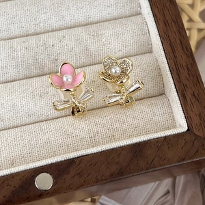 Close-up of asymmetrical flower earrings with pink enamel, white zircon and pearl inlay