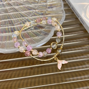 Detail of beaded bracelet with pink gradient enamel mermaid tail charm and gold accents