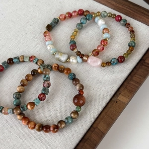Macro shot of assorted natural stone bracelets with tiger eye, strawberry crystal and pearls