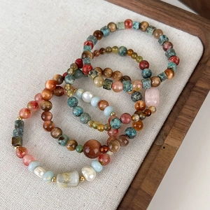 Detail of beaded bracelets with turquoise, agate, and pearls on a wooden tray