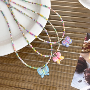 Gros plan d'un collier de perles colorées avec pendentifs papillon en résine pastel