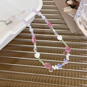 Détail d'un collier de perles rose avec tulipe et cœur et fermoir mousqueton en métal
