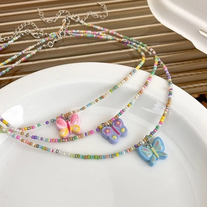 Gros plan détaillé de trois colliers de perles colorées avec pendentifs papillons