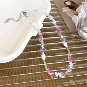 Gros plan des perles de tulipe rose et charms cœur sur un collier de perles artisanal