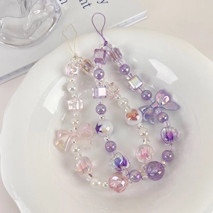 Macro view of sweet purple bow phone charms with aurora beads on a white decorative plate