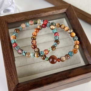 Detailed shot of ethnic style multi-colored stone beaded bracelets in a wooden display tray