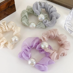 Detail view of five assorted pastel mercerized yarn scrunchies with large pearl accents