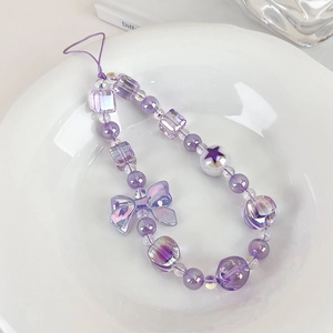 Macro view of purple beaded phone charm with iridescent bow and star beads on a tray