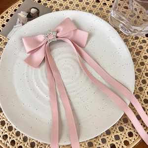 Detailed view of pink satin bow hair clip with sparkling rhinestone star and long ribbons
