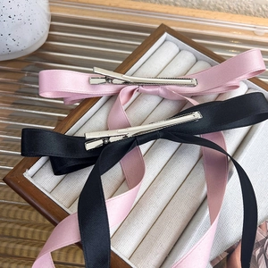 Detalle de pinzas para el cabello con lazos de satén rosa y negro en bandeja
