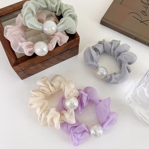 Close-up of colorful chiffon scrunchies with large iridescent pearls in pastel colors