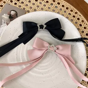Detailed shot of pink and black satin bow hair clips with rhinestone star accents on a ceramic plate