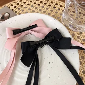 Detail of pink and black satin bow hair clips with long ribbons and rhinestone accents