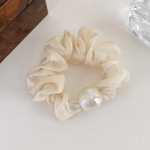 Close-up of a cream mercerized organza scrunchie featuring a large iridescent pearl detail
