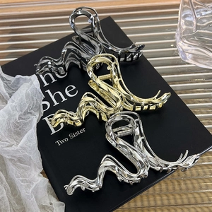 Three metallic hair claws in silver, gold and grey on a decorative black display box