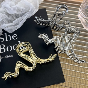 Detail of three liquid metal hair claws in gold, silver, and gun grey wavy line designs