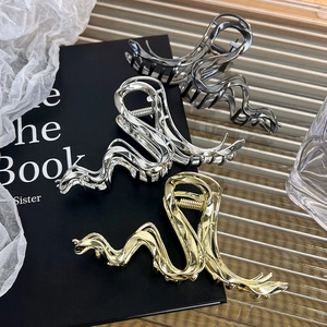 Detailed view of wave-shaped large metal hair claws in gold, silver, and black chrome colors