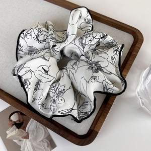Close-up of vintage ink-wash floral scrunchie on a wooden tray with soft lighting