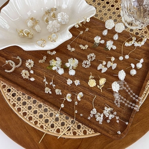 Detail of floral earrings collection featuring pearls and gold flower petals in a tray