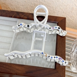 Matte silver star shark hair clip with colorful crystals on a wooden jewelry box
