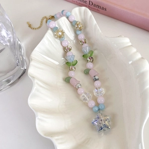 Détail du collier de perles fleuries avec pétales roses et pendentif étoile violette
