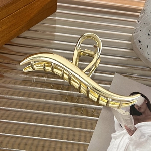 Close-up of large gold metal hair claw clip with sleek curved lines and sturdy spring