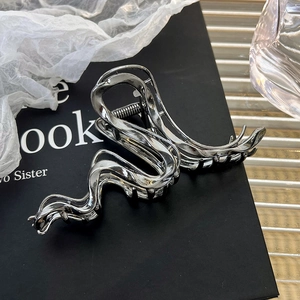 Detailed macro view of liquid metal wave hair claw with chrome silver finish and strong spring