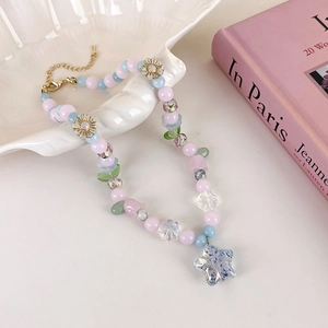 Détail du collier de fleurs en perles avec pendentif étoile bleue et chaîne réglable dorée