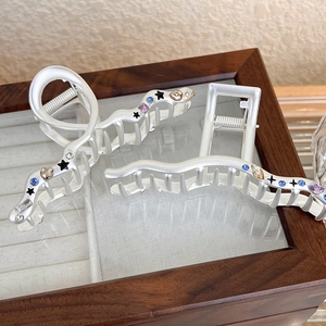 Detail of silver matte hair claws with colored rhinestones and black stars on wood