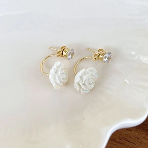 Close-up of elegant gold flower earrings with pearls and zircon on a shell tray