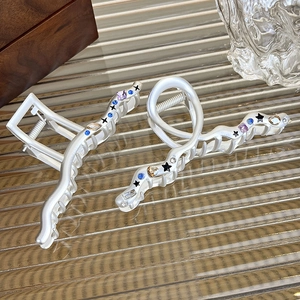 Detail of silver alloy claw clips with wave patterns and colorful zircon star inlay