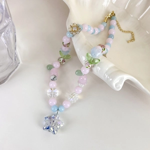 Détail du collier de perles pastel avec charms floraux et pendentif étoile brillante