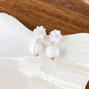 Detail of floral earrings featuring white petals and elegant translucent bell charms
