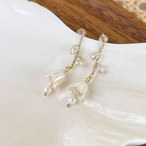 Detail of lily of the valley earrings with white pearls and delicate golden leaves