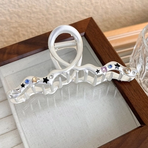 Detail of matte silver metal hair claw with colorful rhinestones and black star patterns