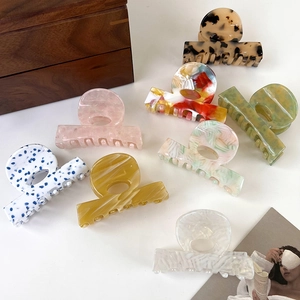 Macro display of eight colorful acetate hair claws featuring marble and floral patterns
