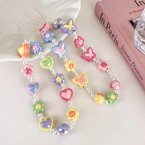 Détail de dragonnes de téléphone en perles avec breloques papillon, cœur et fleurs colorées