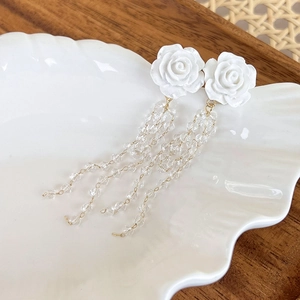 Detail of white rose long tassel earrings with clear beads and gold metal links