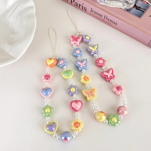 Gros plan de bijoux de téléphone avec perles papillons en résine, cœurs et nacre