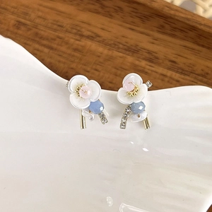 Detail of flower earrings with shell petals, pink beads, and pearl fringe on white tray