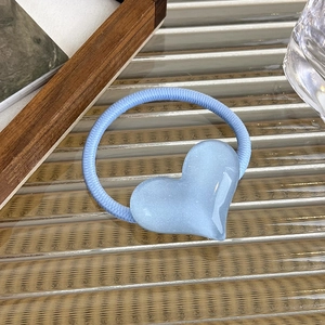 Detail of light blue heart-shaped hair tie with a frosted glitter finish on textured glass